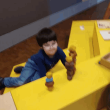 a young boy wearing glasses is playing on a yellow block