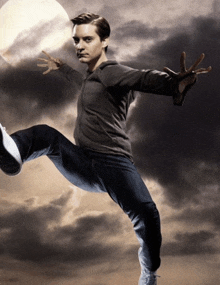 a man kicks a soccer ball in the air with a cloudy sky in the background