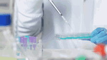 a person in a lab coat is using a pipette to pour liquid into a test tube