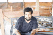 a man in a black shirt sits on a metal bench