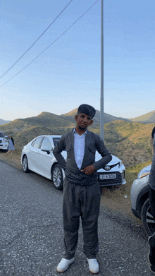 a man standing in front of a white car with a license plate that says t2 e 3636