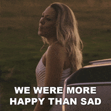 a woman standing next to a car with the words " we were more happy than sad " below her