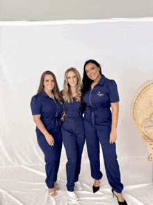 three women posing for a picture with one wearing a blue jumpsuit