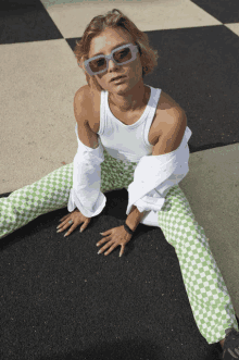 a woman wearing sunglasses and green checkered pants