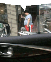 a man and a woman are standing next to a motorcycle in front of a store .