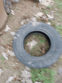 a tire is laying on the ground with a few leaves around it