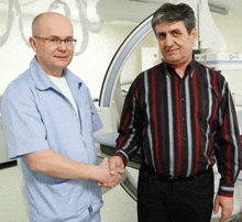 a man in a striped shirt shakes hands with a doctor in a hospital