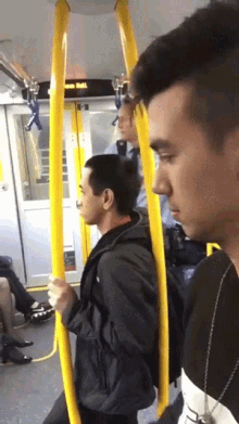 a man holding a yellow railing on a bus with a sign above him that says ' bus rail '