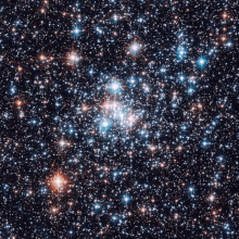 a cluster of stars in the night sky with a red star in the center