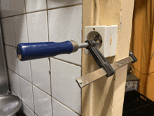 a blue clamp is attached to a white electrical outlet on a wall