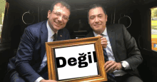 two men in suits hold a picture frame with the word degil on it