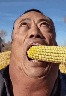 a man is eating a corn on the cob with his mouth open .