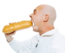 a bald man is eating a long loaf of bread .