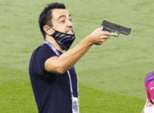 a man wearing a mask is pointing a gun at someone on a field .