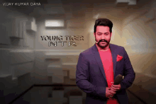 a man in a suit stands in front of a sign that says " young tiger ntr "