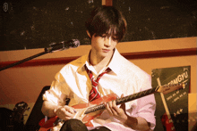 a man playing a guitar in front of a sign that says omgyu