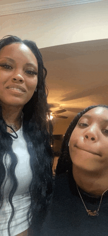 two women are posing for a picture with one wearing a necklace that says faith