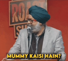 a man in a turban is speaking into a microphone and the words mummy kaisi hain are above him