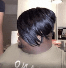 a man with a wig on his head and a beard is sitting at a table in a kitchen .