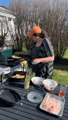 a woman in an orange hat is preparing food outside