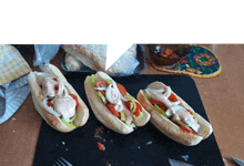 three hot dogs are sitting on a cutting board on a table