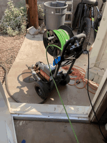 a green hose is attached to a pressure washer on a patio