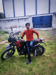 a young man in a red shirt is kneeling on a motorcycle