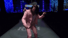 a man in a pink suit is dancing on a stage in front of a sign that says ' carne che ' .