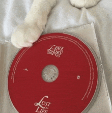 a cat 's paw rests on top of a lana del rey cd