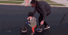 a man is teaching a child how to ride a balance bike .