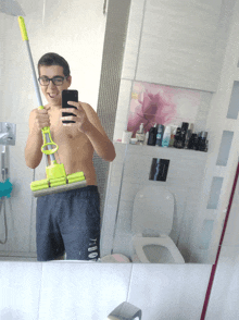 a young man taking a selfie with a mop in his hand