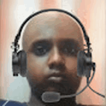 a bald man wearing headphones with a microphone on his head .