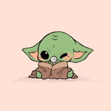 a baby yoda from star wars is sitting on a blanket and eating a cookie .