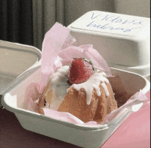 a cake with a strawberry on top of it in a styrofoam container .