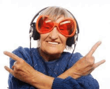 an elderly woman wearing headphones and red sunglasses is pointing at something .