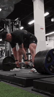 a man is lifting a barbell in a gym with a sign on the wall that says " no smoking "