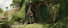 a statue of a wizard standing in front of a hobbit house