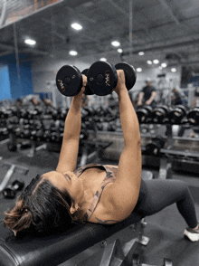 a woman is lifting a pair of dumbbells with the number 5 on the bottom