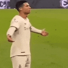 a soccer player is standing on a field with his arms outstretched and a white shirt on .