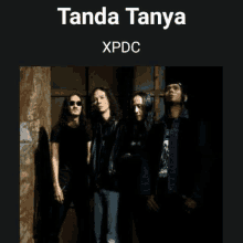 a group of men standing next to each other in front of a wall with the words tanda tanya xpdc on the bottom .