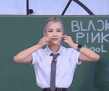 a girl in a school uniform is standing in front of a blackboard that says blackpink school