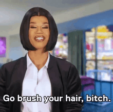 a woman in a suit and white shirt is talking about brushing her hair .