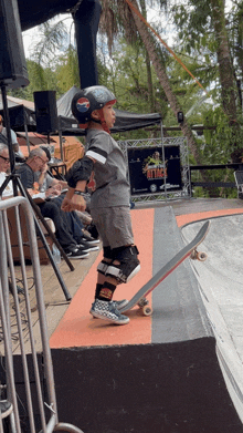 a young boy wearing a helmet and knee pads is riding a skateboard down a ramp