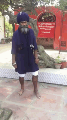 a man in a blue turban stands in front of a red building with a sign that says ' shree ram '