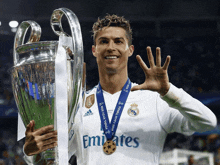 a man holding a trophy with a medal that says emirates