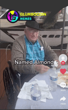 a man in a wheelchair named almond sits at a table with bottles of water