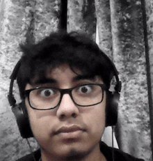 a man wearing glasses and headphones looks at the camera .