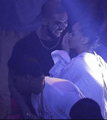 a man and a woman are standing next to each other in a dark room with a purple light behind them