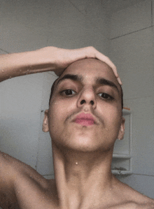 a man without a shirt is taking a selfie in a bathroom