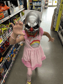 a little girl wearing a clown mask and a pink dress